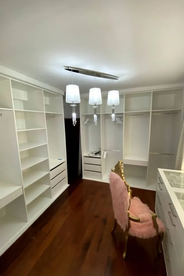 Closet branco com espelho e iluminação no teto
