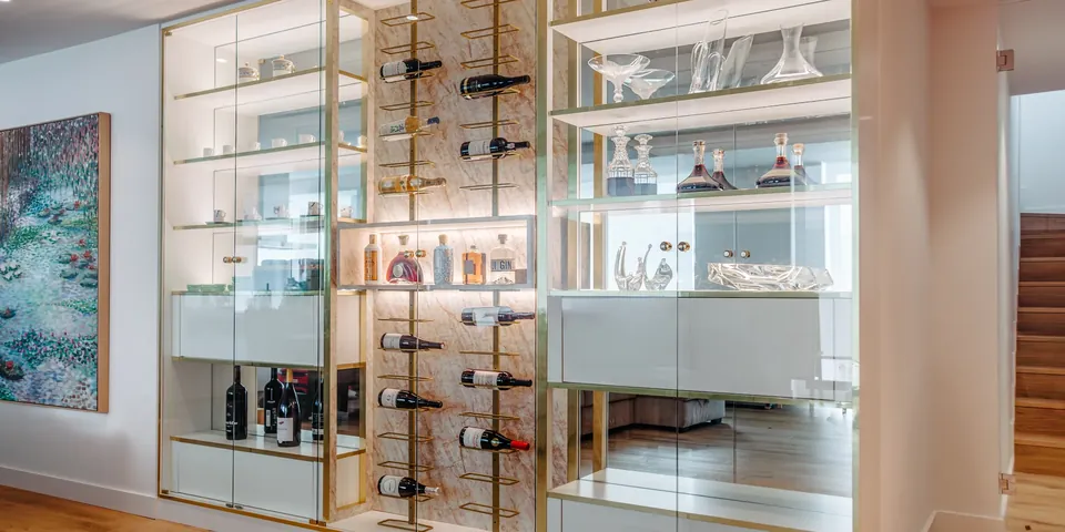 Vitrine em vidro com estrutura dourada e garrafeira integrada